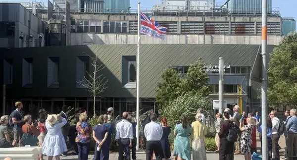Crowd watching the Armed Forces Day flag being raised outside the UHS main entrance.