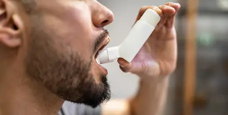 Close up of man using asthma inhaler