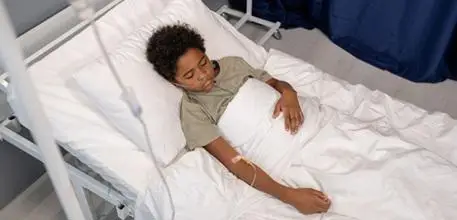 Child asleep in a hospital bed with a drip in his arm and oxygen tube in his nose