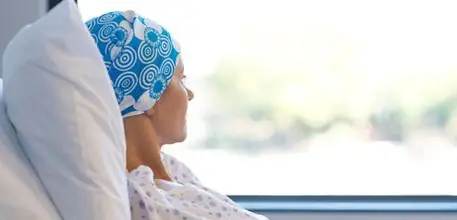 Cancer patient in a hospital bed looking out of a window