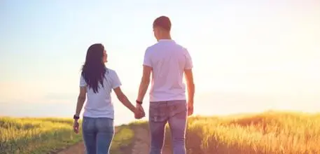 Couple holding hands walking through a field
