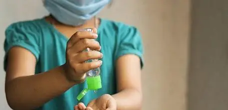 Child wearing mask and using hand gel