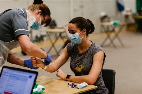 Nurse attaching wristband at COVID-19 vaccination hub