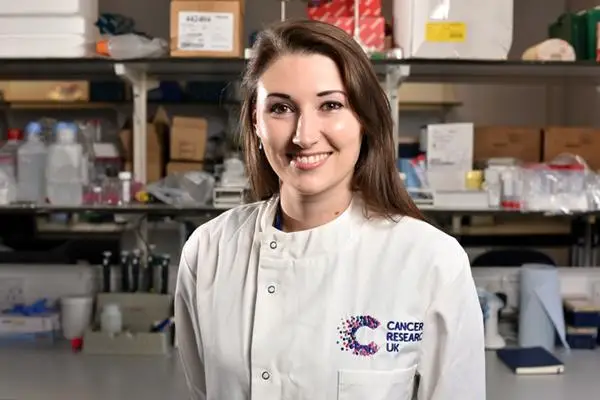 Dr Catherine Pointer in a laboratory wearing a labcoat with the Cancer Research UK logo.