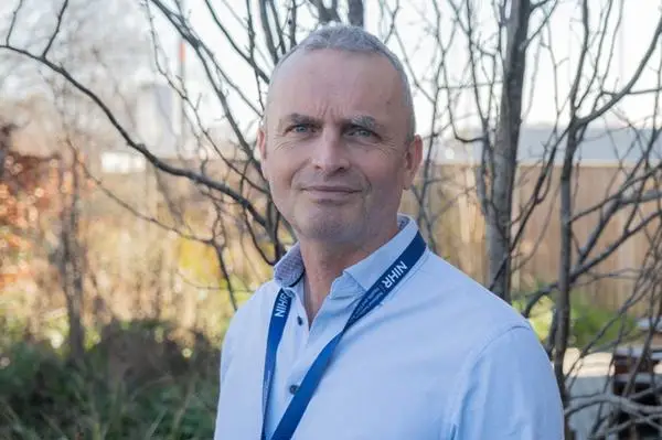 Dr Andrew Bates with trees behind him