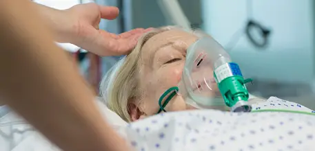 Elderly woman wearing oxygen mask sleeps in hospital