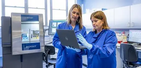 Two members of the team looking at a laptop in the University's Flow Cytometry Core Facility.