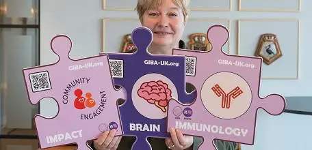 Jessica Teeling holding three giant puzzle pieces saying 'impact', 'brain' and 'immunology'.