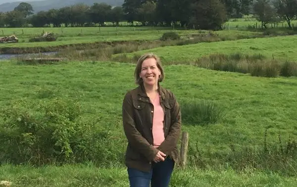 Hazel Southam in a field with a stream behind her