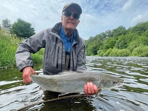 James pictured holding a fish in a river
