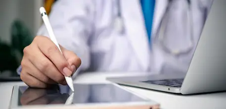 Close up of medical professional working on laptop and tablet 