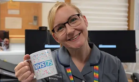 Person holding NHS 75 mug