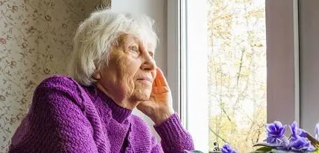 Older woman at home looking out of window