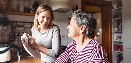 Older woman doing washing up with daughter