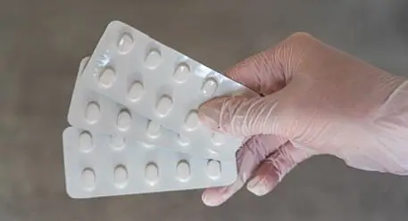 Gloved hand holding three antibiotic strips