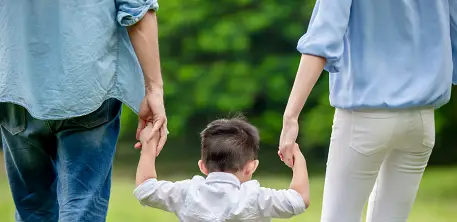 Young boy holding hands with his mum and dad