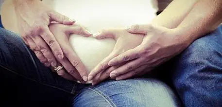 Couple making heart shape over bump