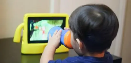 A young boy watches a tablet in a bright yellow case