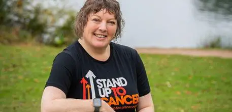 Caroline Palmer wearing a Stand Up to Cancer T-shirt, with a lake in the background