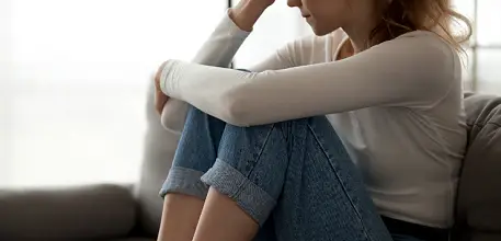 Upset teenage girl sitting on a sofa 