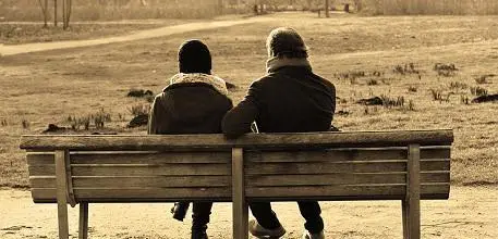 Two people sat on a bench talking