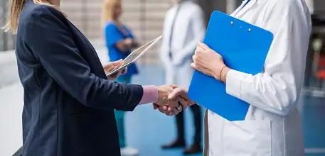 Two people shaking hands, one in a suit, one in a lab coat