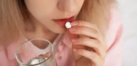 Woman taking a folic acid supplement with a glass of water
