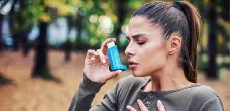 Woman in woods using her inhaler